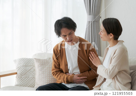 腹痛に苦しむ夫と励ます妻 121955503