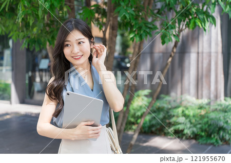オフィス街でタブレット端末を持つビジネスウーマン 121955670