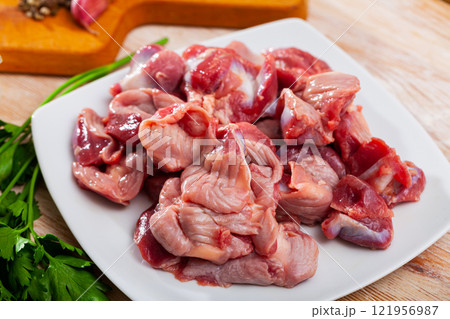 Raw chicken gizzards and greens on wooden surface 121956987