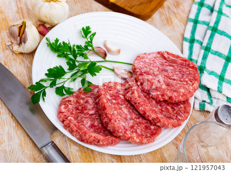 Cooking ingredients, raw burger cutlets on board Cooking ingredients, raw burger cutlets on board 121957043