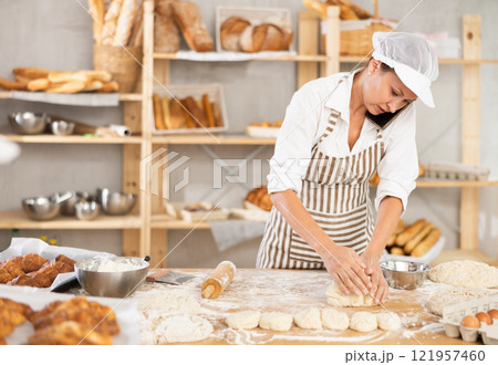 Adult woman baker molding pieces of dough 121957460