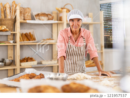 Elderly female baker posing in workshop Elderly female baker posing in workshop 121957537
