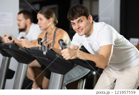 Focused guy works out with stationary bicycle during class at fitness club 121957559