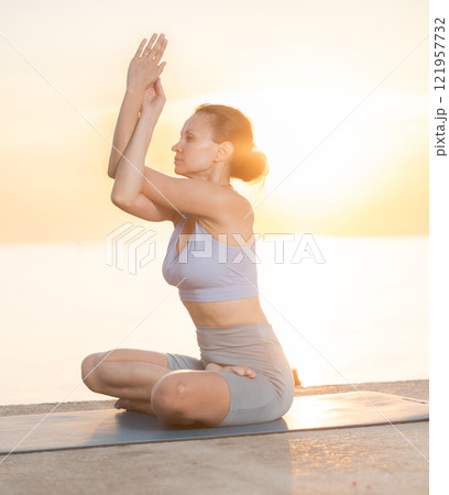 Near sea during sunset, girl performs variations of padmasana 121957732