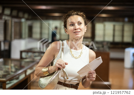 Woman curiously observing antique artifacts in historical museum Woman curiously observing antique artifacts in historical museum 121957762