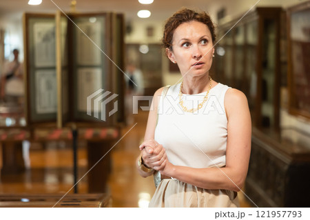 Woman curiously observing antique artifacts in historical museum Woman curiously observing antique artifacts in historical museum 121957793