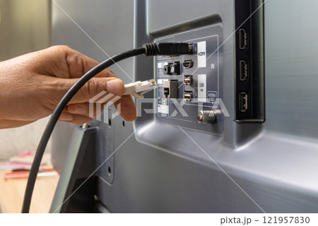 Man connects internet cable to the TV. 121957830