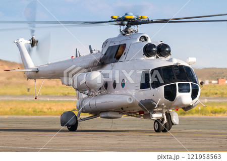 Taxiing a white passenger helicopter on the airport apron 121958563