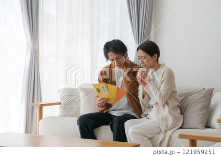 督促状の封筒を見る夫婦 121959251