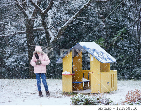 冬の公園で楽しく雪遊びしている小学生の女の子の様子 121959510