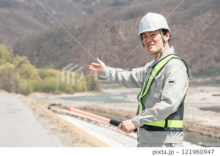 河川敷・堤防で交通整理をする男性ガードマン 121960947