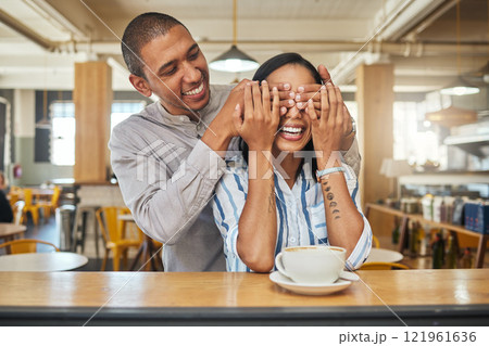 A man covering a happy womans eyes for as a greeting, for a surprise and on a restaurant, cafe or fast food store date. An in love, dating or married young couple smile while on hot coffee lunch 121961636