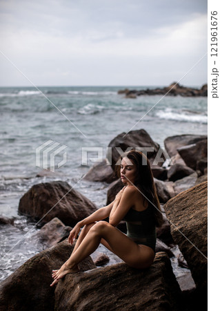 Serene Seaside Retreat A woman enjoying her time on a beautiful rocky shoreline by the ocean 121961676