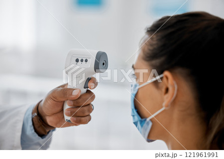 Compliance, healthcare and covid with a doctor scanning a patient temperature with infrared thermometer, checking for a fever. Concerned woman suffering from corona, flu or cold in exam or consult 121961991