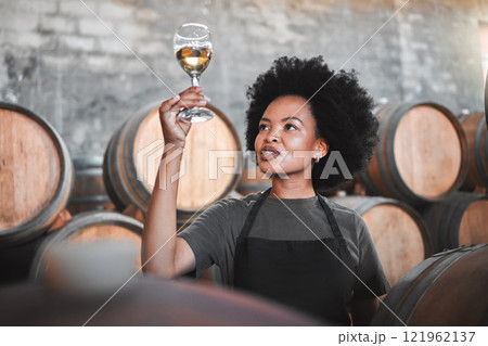 Black woman tasting wine at a winery, looking and checking the color and quality of the years produce. Young African American sommelier proud of the new addition, analyzing white wine in a cellar Black woman tasting wine at a winery, looking and checking the color and quality of the years produce. Young African American sommelier proud of the new addition, analyzing white wine in a cellar 121962137
