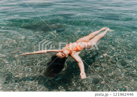 Woman Bikini Floating - A woman in a bikini floats on her back in clear turquoise water. Woman Bikini Floating - A woman in a bikini floats on her back in clear turquoise water. 121962446