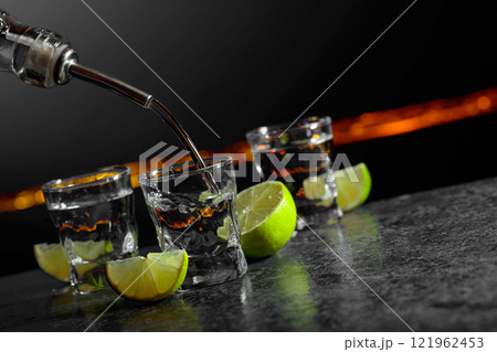 Strong alcoholic drink and lime slices on a dark background. 121962453