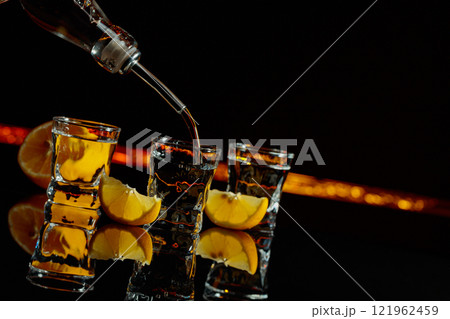 Vodka and lemon slices on a black background. Vodka and lemon slices on a black background. 121962459