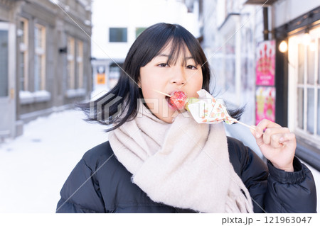 冬の北海道でいちご飴を食べる日本人の女性 121963047