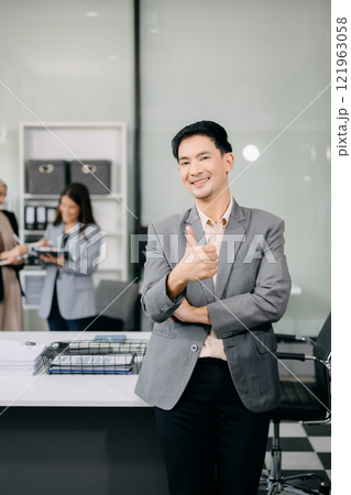 Young attractive Asian male office worker business Asian male office worker business suits smiling at camera in office . teamwork startup concept Young attractive Asian male office worker business Asian male office worker business suits smiling at camera in office . teamwork startup concept 121963058