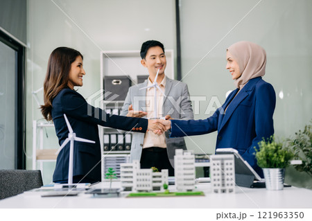 Group of diverse multiethnic businesspeople standing neare table looking at model of building from residential project. Group of diverse multiethnic businesspeople standing neare table looking at model of building from residential project. 121963350