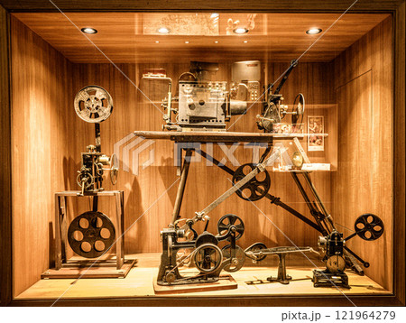 Historic film equipment display showcasing early cinematography techniques in a museum setting. An exhibit featuring vintage film equipment, including projectors and cameras, highlights the evolution  121964279