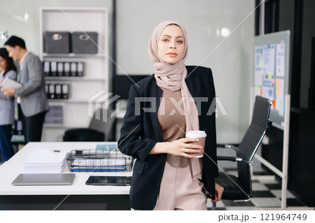 Young attractive female office worker business suits smiling at camera in office Young attractive female office worker business suits smiling at camera in office 121964749