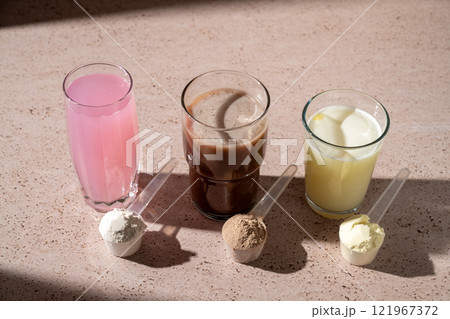 Different protein shake drinks in glasses and protein powder in scoops Different protein shake drinks in glasses and protein powder in scoops 121967372