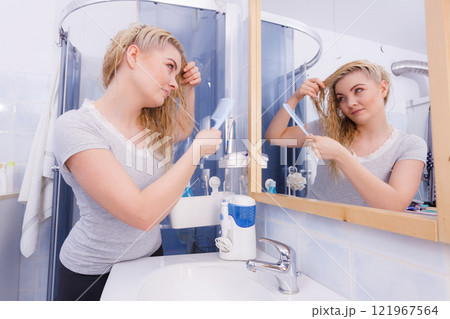 Woman combing her long hair in bathroom Woman combing her long hair in bathroom 121967564