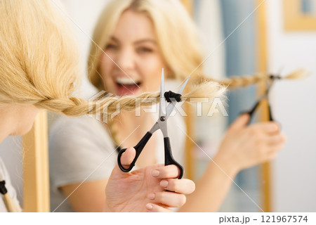 Woman cutting blond braid hair 121967574