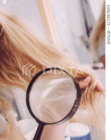 Woman looking at hair ends through magnifying glass Woman looking at hair ends through magnifying glass 121967603
