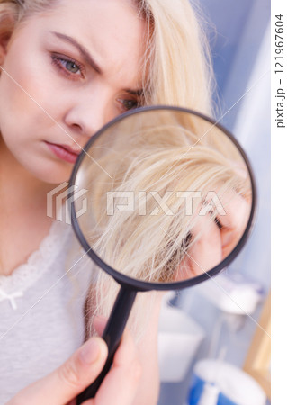 Woman looking at hair ends through magnifying glass Woman looking at hair ends through magnifying glass 121967604