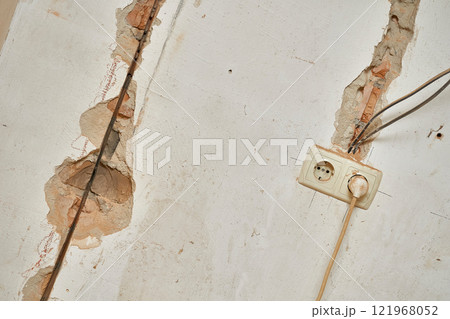 Old brick wall before renovation. Connected socket, wiring, cracks Old brick wall before renovation. Connected socket, wiring, cracks 121968052