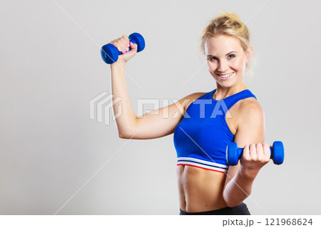 Fit woman lifting dumbbells weights Fit woman lifting dumbbells weights 121968624