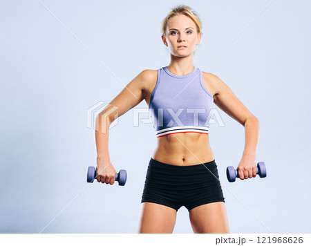 Fit woman lifting dumbbells weights Fit woman lifting dumbbells weights 121968626