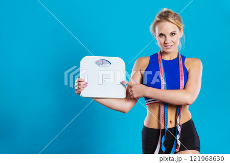 Fit woman with measure tape with weight scale 121968630