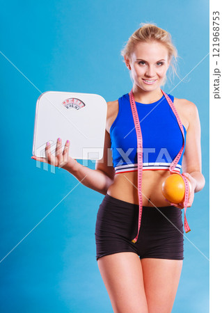 Fit woman holds weight scale grapefruit Fit woman holds weight scale grapefruit 121968753