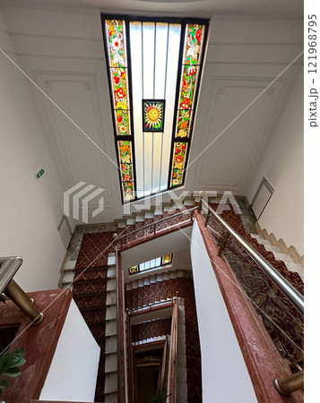Spiral staircase with a vibrant stained-glass ceiling showcasing intricate patterns and colorful motifs. the artistic design and elegant decor a sense of timeless beauty and architectural mastery in 121968795