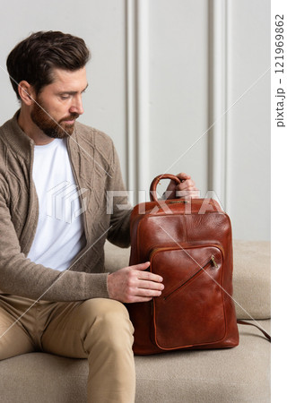 A Stylish and Man sitting with a yellow brown backpack in a Contemporary Modern Setting 121969862