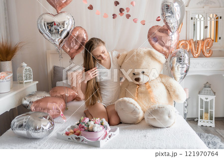 Beautiful young girl at home on the bed in the morning enjoy valentines day celebration with heart shaped balloons Beautiful young girl at home on the bed in the morning enjoy valentines day celebration with heart shaped balloons 121970764