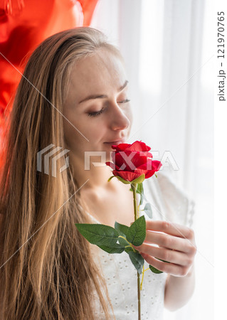Beautiful young girl at home in bedroom in the morning enjoy valentines day celebration with heart shaped balloons Beautiful young girl at home in bedroom in the morning enjoy valentines day celebration with heart shaped balloons 121970765