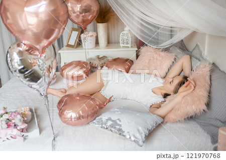 Beautiful young girl at home on the bed in the morning enjoy valentines day celebration with heart shaped balloons 121970768