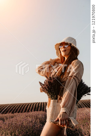 Young Woman in Lavender Field with a Basket of Flowers 121970800