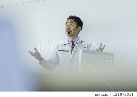 ホワイトボードの前で話をする作業服のミドルエイジの男性　撮影協力：学校法人電波学園 東京電子專門学校 121972011