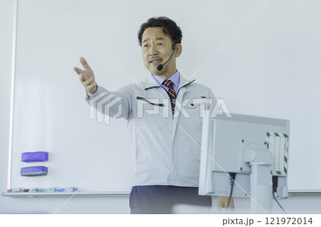 ホワイトボードの前で話をする作業服のミドルエイジの男性　撮影協力：学校法人電波学園 東京電子專門学校 121972014