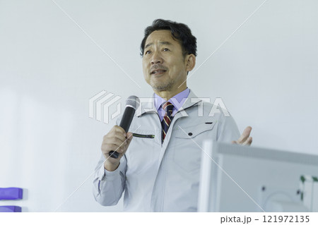 ホワイトボードの前で話をする作業服のミドルエイジの男性　撮影協力：学校法人電波学園 東京電子專門学校 121972135