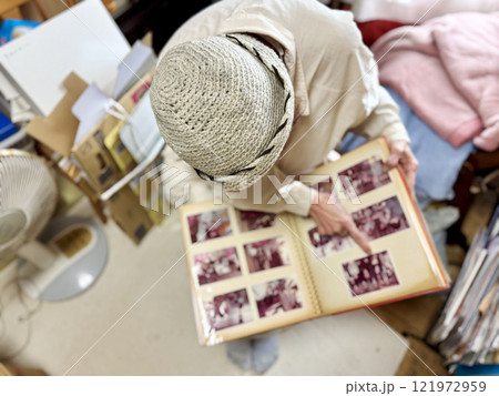 散らかった部屋でアルバムを指さす高齢女性_上から 121972959