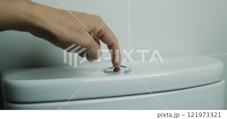 man flushing the toilet in a white-tiled bathroom man flushing the toilet in a white-tiled bathroom 121973321
