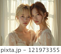 窓際で寄り添う2人の若い女性 121973355