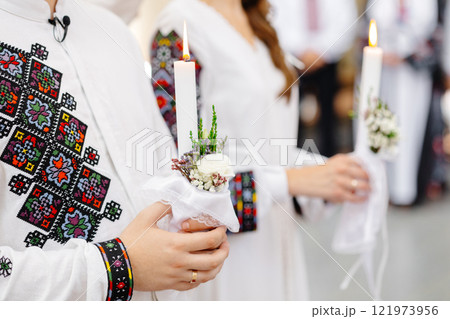 Couple wearing traditional Romanian costume holding candles during a religious ceremony Couple wearing traditional Romanian costume holding candles during a religious ceremony 121973956